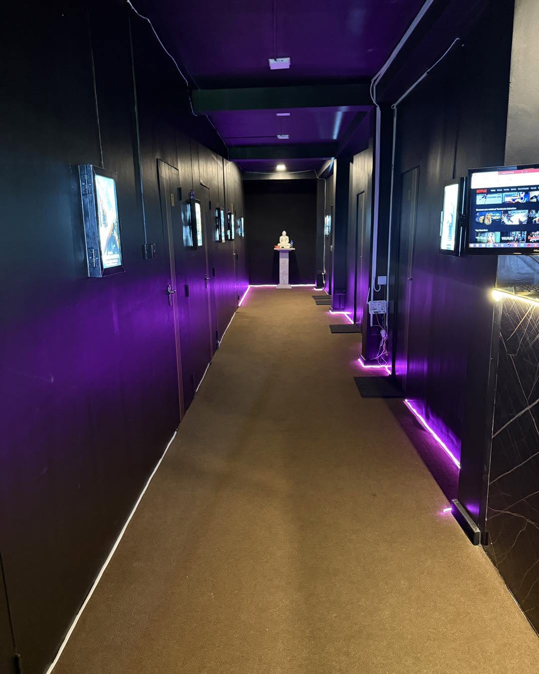 Purple-lit corridor leading to private cinema rooms